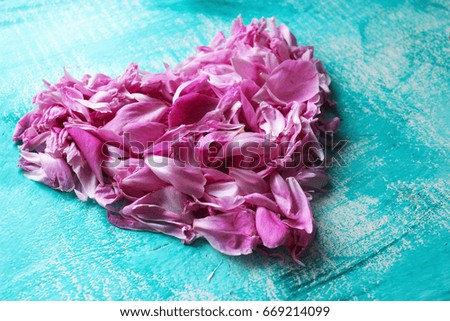 Pink heart made of peony petals on a blue background