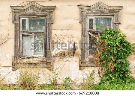 Windows with wooden frame on the old beige wall are covered with metal sheets