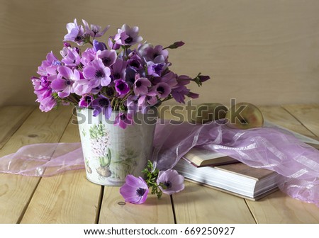 Still life with wild anemones, books and apple on a wooden table close-up 