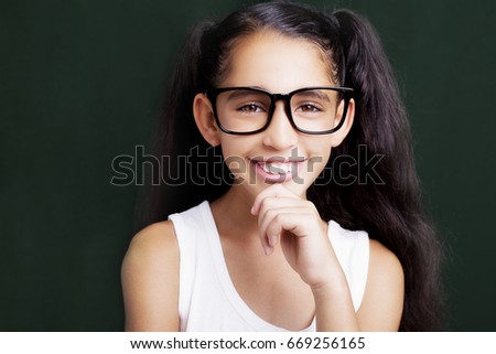 Adorable girl studying with eyeglasses on dark background