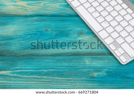 Business workplace with  wireless keyboard on old blue wooden table background. Office desk with copy space