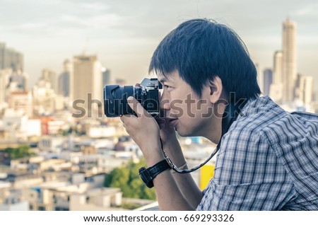Thai photographer or traveller using a professional mirrorless camera in the cityscape for background