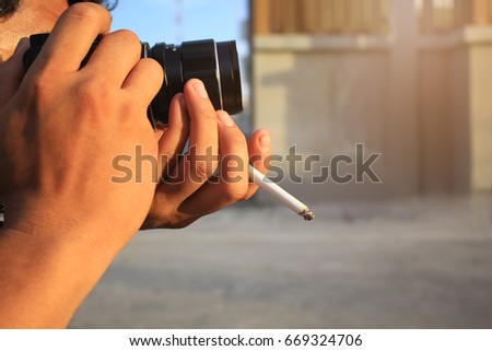 Photographer hand holding smokes a cigarette and holding his camera