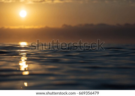Sunrise over a sea with small waves and beautiful clouds in background