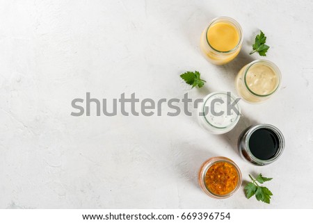 Set of dressings for salad: sauce vinaigrette, mustard, mayonnaise or ranch, balsamic or soy, basil with yogurt. Dark white concrete table. Copy space top view Royalty-Free Stock Photo #669396754