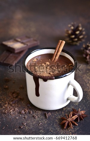 Homemade spicy hot chocolate with cinnamon in enamel mug on a slate,stone or concrete background.