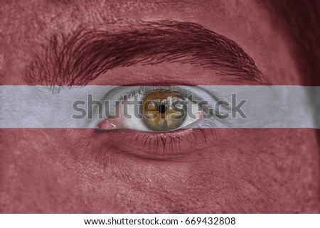 Human face and eye painted with flag of Latvia