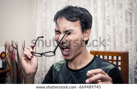 a man with funny accident, he accidentally jab his eye with glasses leg and get painful reaction Royalty-Free Stock Photo #669489745