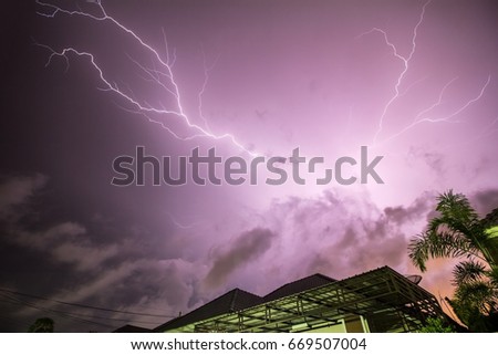 Thunder, lightning storm in the raining night background over a house and palm tree with slow shutter speed.