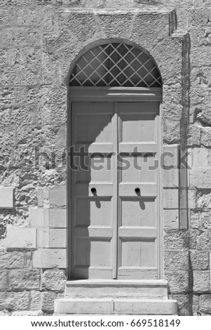 Building with traditional maltese door in historical part of Mdina. The city was founded as Maleth in around the 8th century BC by Phoenician settlers on the island of Malta. Black and white picture