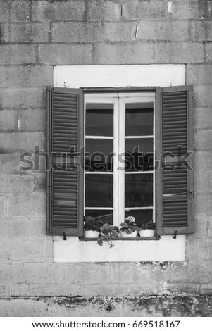 Building with traditional maltese window decorated with fresh flowers in Valletta. Black and white picture