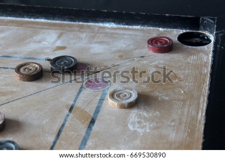 A game of carrom with man on the board, queen near hole, win game