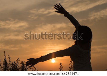 Silhouette of a young asian woman enjoying flowers and nature sunset
