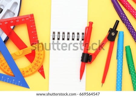 Multicolored rulers and pen on yellow background
