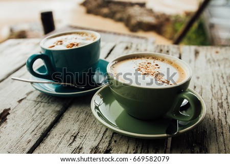 Two cups cappuccino coffee stand on wooden table. Green and blue cup cofe. Close up cups strong coffee stand on white vintage wooden background table. Royalty-Free Stock Photo #669582079