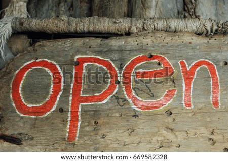 Text sign is open on a wooden board. Close up sign open on wooden background. Sign in the cafe. Red paint. Handmade. Written red letters text open on signboard