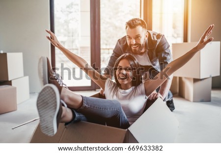 Happy couple is having fun with cardboard boxes in new house at moving day. Royalty-Free Stock Photo #669633382