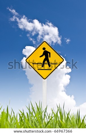 A yellow man walking sign with nice sky