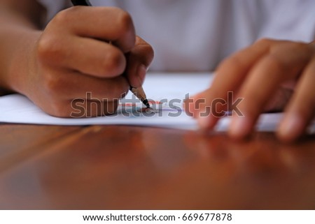 The boys' hands are drawing and Coloring cartoon in white paper on wooden table.