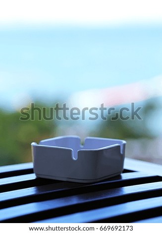 Ashtray on wooden table with sky ocean blur background