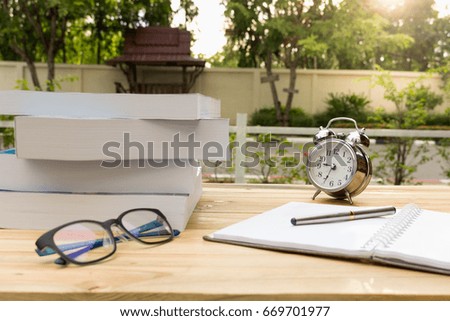 Desk on the balcony with a notepad book watches  glasses and pen on the table