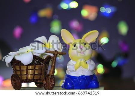 the white plumeria flowers on rattan tricycle and rabbit doll and many color bokeh