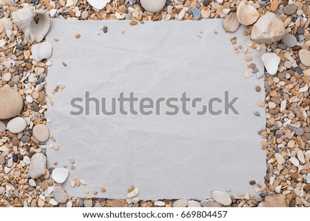 Small sea stones and shells, on a textured paper, with a free space under the text, title, ad, menu or picture.