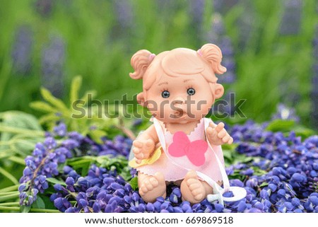 Doll with the  garden flowers on the background. l