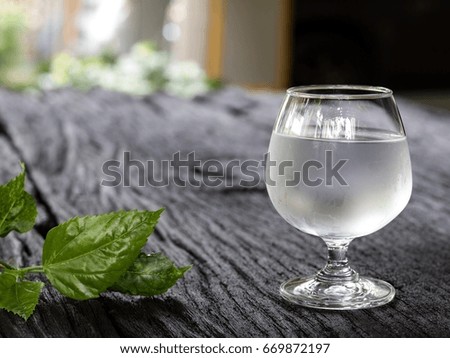 Cold water in a glass with leaves on wooden boards.