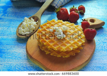 Belgian waffles with strawberries, blueberries and syrup on wooden table