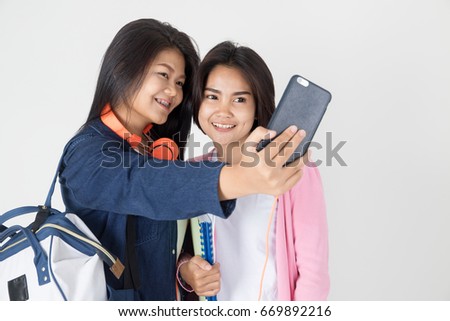 Portrait of Happy asian student with stationery tool  and take a photo by smart phone on gray background