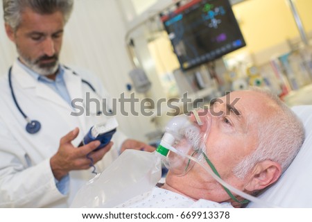doctor near patient wearing oxygen mask in hospital room Royalty-Free Stock Photo #669913378