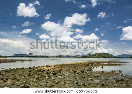 Shingle beach in Tung Chung, Hong Kong. Hong Kong international airport and Ngong Ping 360 are also shown in here. Wide angle background eith blue cloudy sky and wetland.