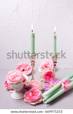 Summer flowers and burning candles  on grey textured background.  Selective focus.
