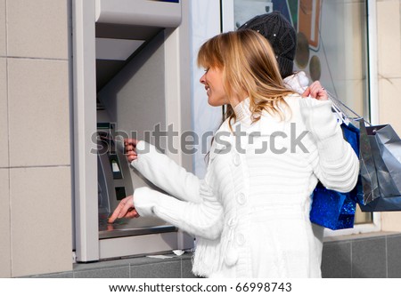 Happy girls withdrawing money from credit card at ATM