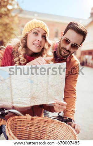 Young couple is looking for direction.Woman is pointing some direction, holding a city map.