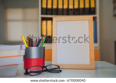 photo Frame and book and colorful crayons on the table in library .