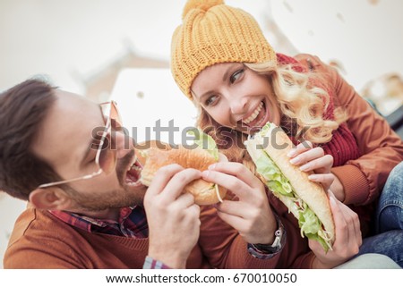 Young happy couple eating together outdoors and smiling.