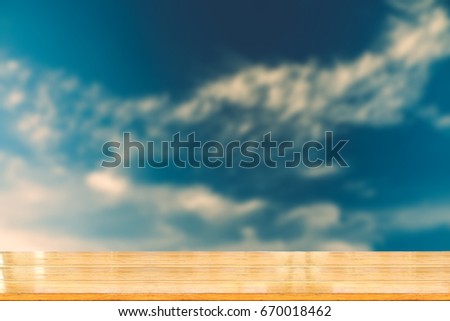 Blurred image of blue sky with wooden tabletop use for products display