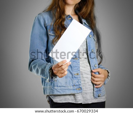 The girl in the blue denim shirt holds the white empty piece of paper. Ready for your design. Closeup. Isolated