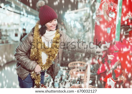 Pretty young cheerful  girl buying floral compositions at Christmas market