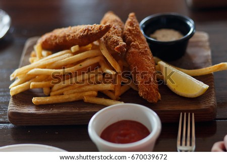 Fried cod with french fries on wooden tray