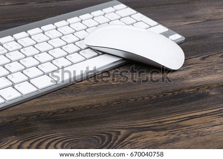 Close up view of a business workplace with wireless computer keyboard, keys and mouse on old dark natural wooden table background. Office desk with copy space