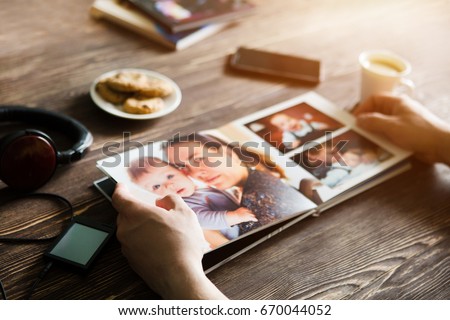 the Hand man holding a family photo album  against the background of the a wooden table
 Royalty-Free Stock Photo #670044052