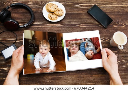 the Hand man holding a family photo album  against the background of the a wooden table
