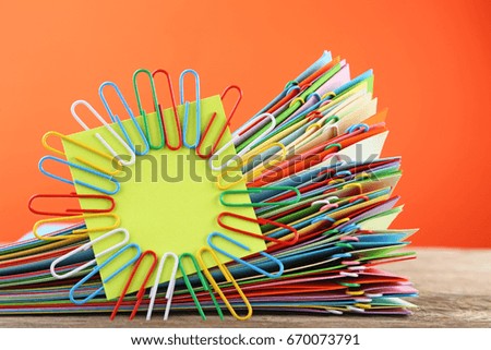 Stack of colored papers with paperclips on wooden table