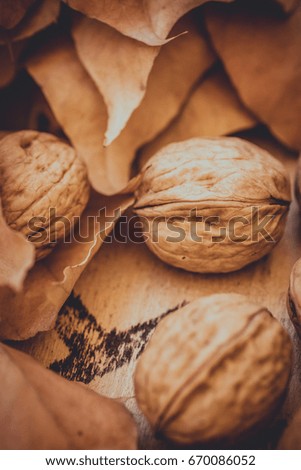 Whole walnuts, dry fallen autumn leaves, brown, yellow colors, weathered wood garden box, cozy atmosphere, toned, copyspace, overlay ready, greeting card, Thanksgiving