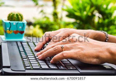 woman is working outdoor,laptop typing on the table in front of her house,in the beautiful garden on the beautiful day and she feel happy with her home work,and enjoy black coffee no sugar for healthy