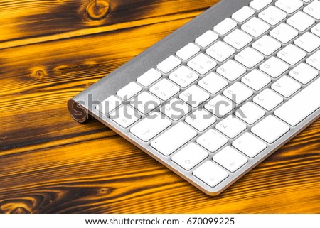 Close up view of a business workplace with wireless computer keyboard, keys on old dark burned wooden table background. Office desk with copy space