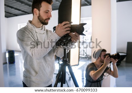 Creative photographers work in studio. Two people with cameras during the studio session. Creative photo and video team shooting in interior